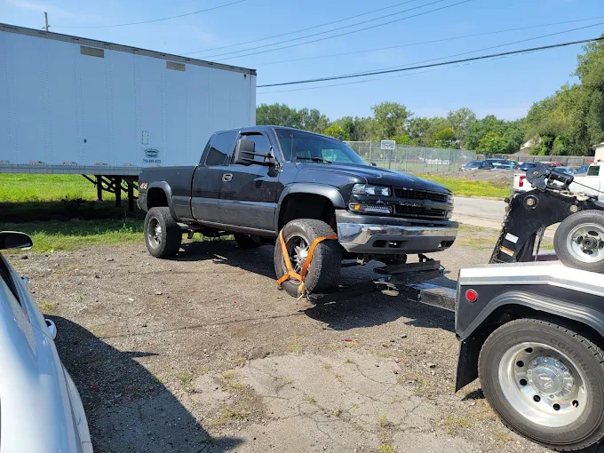 Dark pickup truck being loaded onto a tow truck wheel lift