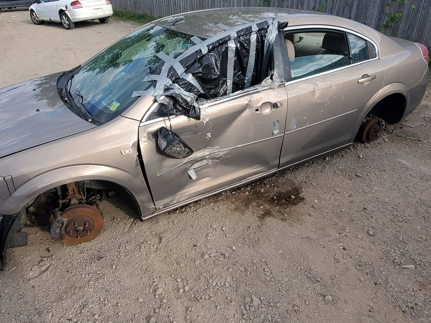 Wrecked sedan with missing wheels and taped-up window